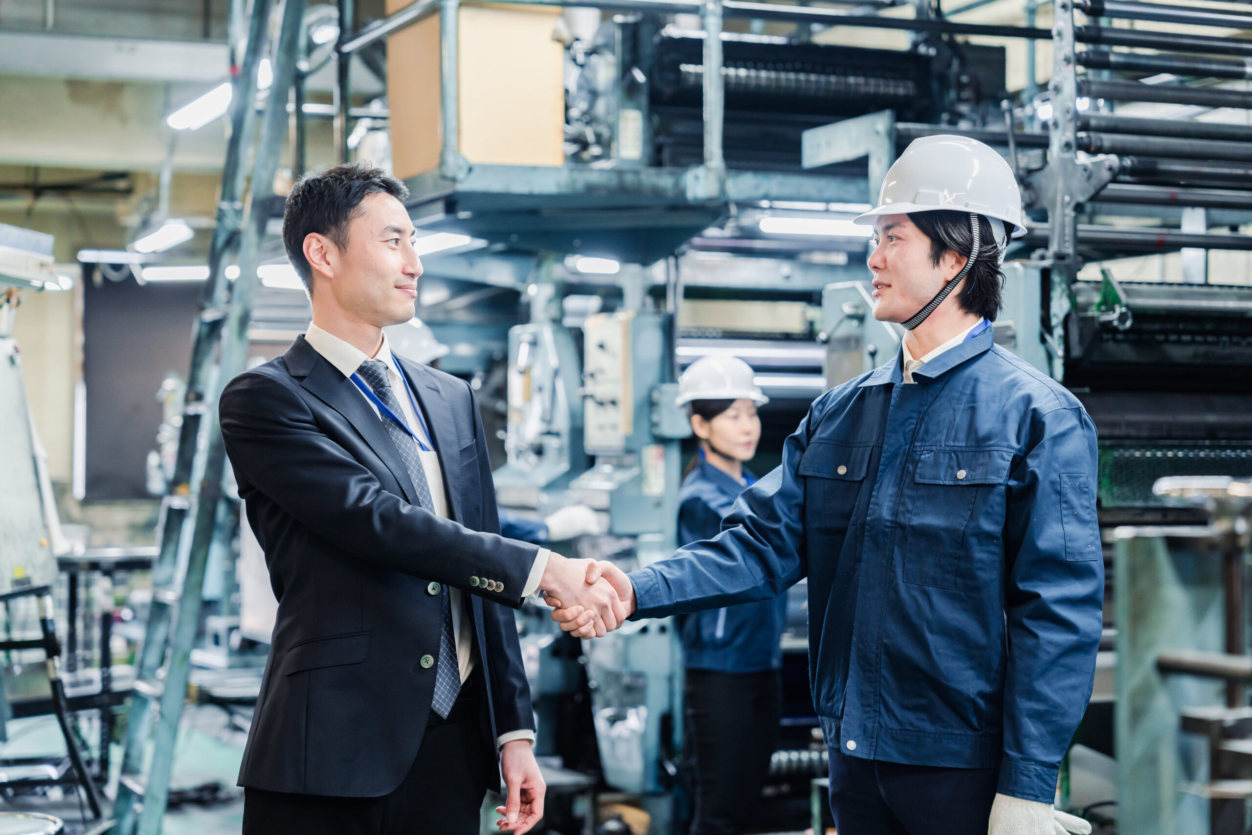 Businessman and supplier shaking hands in tech factory