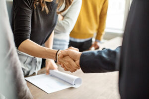 The hands of a woman and man shaking over an agreement.