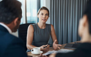 Woman in conference room speaking to colleagues in a meeting.